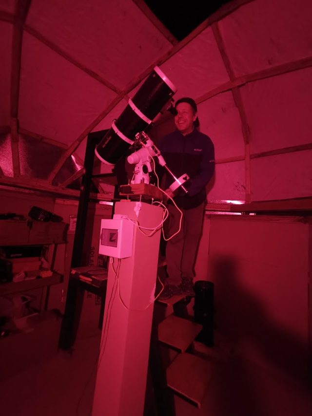 Persona observando por el telescopio bajo luz roja
