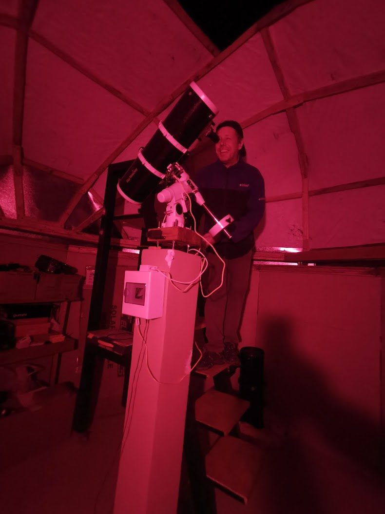 Persona observando por el telescopio bajo luz roja dentro del domo