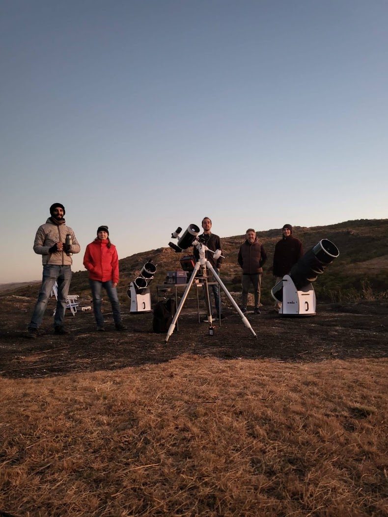 Grupo de personas con telescopios preparando la observación al atardecer